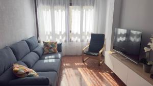 a living room with a blue couch and a television at Puerta del Mar 2 in Adra
