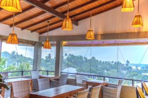 a restaurant with tables and chairs and large windows at Amera Hiriketiya in Dickwella