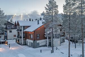 a house is covered in snow with trees at Levillas Karhunvartija 9 in Levi