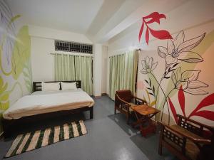 a bedroom with a bed and flowers painted on the wall at White Lotus in North Lakhimpur +7 photos