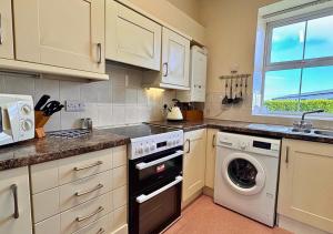 a kitchen with a washing machine and a window at Seacrest Cottage in Conwy