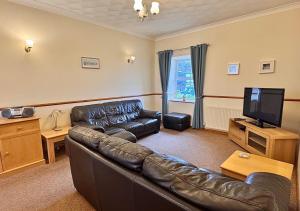 a living room with a leather couch and a flat screen tv at Seacrest Cottage in Conwy