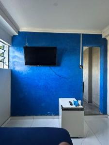 a living room with a blue wall with a tv at Pousada Amizade in Foz do Iguaçu +6 photos