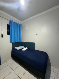 a bedroom with a blue bed with blue curtains at Pousada Amizade in Foz do Iguaçu