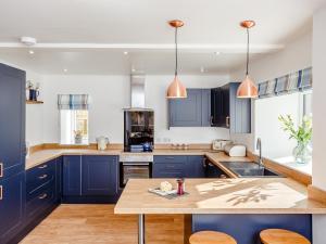 a kitchen with blue cabinets and a wooden table at Knocknahighle in Cromdale