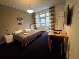 a bedroom with a bed and a table and a window at B&B De Hofnar Maastricht in Maastricht