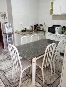 a kitchen with a table with four chairs and a microwave at Nossa Senhora Aparecida Apartment in Cachoeira Paulista +3 photos