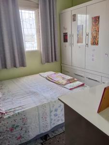 a bedroom with a bed and cabinets and a desk at Nossa Senhora Aparecida Apartment in Cachoeira Paulista