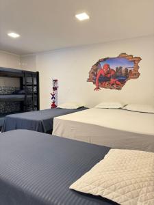 a room with two beds and a painting on the wall at Pousada Pazzini in Guarujá