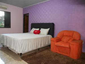 a bedroom with a bed and an orange chair at Chacara barro branco in Foz do Iguaçu +80 photos