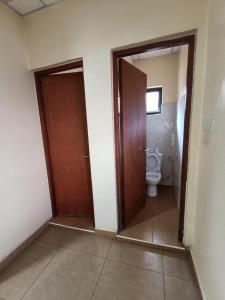 a bathroom with a toilet and a wooden door at Hacienda Villa in Juja