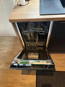 an open dishwasher with a stack of books on a table at Apartment Timeout in Welschbillig