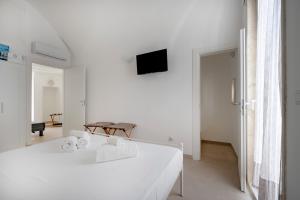 a white room with a bed and a tv on the wall at Ranieri rooms & relax stella in Mola di Bari