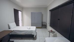 a white room with a bed and a chair at Jahu Center Lodge in Jaú