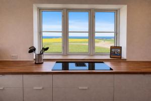 a kitchen with two windows and a table with a laptop at Solhjem Bornholm - Top Rated Sea View Stay in Gudhjem