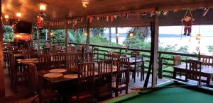a restaurant with wooden tables and chairs and a pool table at Bela Vista Lodge in Novo Airão