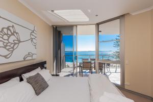 a bedroom with a bed and a view of the ocean at Sandcastle Apartments in Port Macquarie