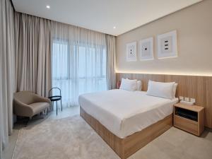 a bedroom with a large white bed and a chair at The Code Residence - ذا كود ريزيدنس in Kuwait +37 photos