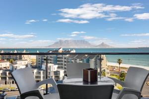 a table and chairs on a balcony with a view of the ocean at Aquarius Luxury Suites in Bloubergstrand
