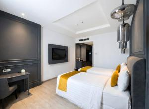 a bedroom with a bed and a desk and a tv at Hotel Shalva Jakarta in Jakarta