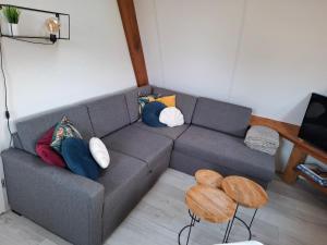 a living room with a gray couch with pillows at B&B Buiten Gewoon Callantsoog in Callantsoog