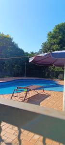 a picnic table and an umbrella next to a swimming pool at Chacara barro branco in Foz do Iguaçu