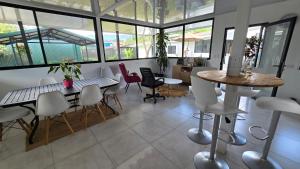 a dining room with a table and chairs and windows at Mango Coliving Rooms for Digital Nomads in Uvita