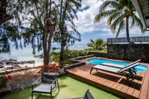 a backyard with a swimming pool and a table and chairs at Beach, Blue Sea, Sunset and Private Pool in Rivière Noire