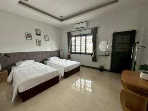a bedroom with two beds and a window at Cocoon Casa in Hat Yai