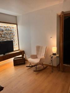 a living room with a chair and a flat screen tv at Le Roche-Velours in Paray-le-Monial