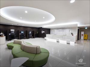 a large lobby with a green couch and chairs at Daiwa Roynet Hotel Kawasaki in Kawasaki