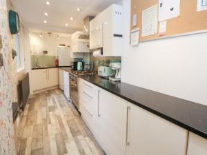 a kitchen with white cabinets and black counter tops at Kirkham House in Matlock