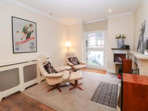 a living room with two chairs and a tv at Kirkham House in Matlock