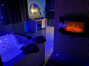 a bathroom with a tub with a fireplace in it at Suite Casanova avec SPA & Escape Love Game - Doux Bleu Jeux in Niort +1 photo