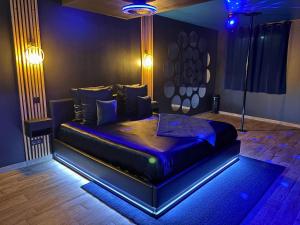 a bedroom with a bed in a room with blue lights at Suite Casanova avec SPA & Escape Love Game - Doux Bleu Jeux in Niort