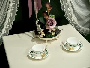 a table with two tea cups and a vase of flowers at 大同GardenHotel 大阪西九条Annex in Osaka