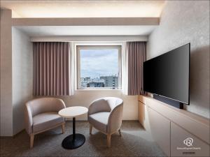a hotel room with a tv and two chairs and a table at Daiwa Roynet Hotel Kawasaki in Kawasaki