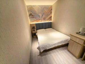 a small bedroom with a bed and a painting on the wall at 木子酒店 in Nanjing