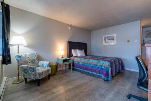 a bedroom with a bed and a chair and a lamp at Days Inn by Wyndham Burns in Burns +20 photos