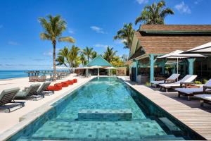 a swimming pool next to a resort with chairs and the ocean at Four Seasons Resort Seychelles at Desroches Island in Desroches +114 photos