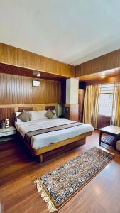 a bedroom with a large bed and a rug at Hotel Marvel International And Restaurant in Darjeeling