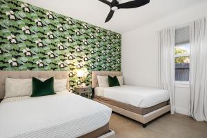 two beds in a bedroom with a floral wall at Delray Oasis - Private Pool - Fenced Yard - Parking - Laundry - Full Kitchen - Convenient Location in Delray Beach +23 photos