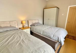 a bedroom with two beds and a cabinet at Sunset Cottage in Llanddulas
