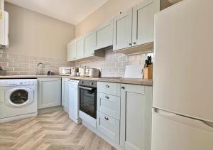 a kitchen with white cabinets and a washer and dryer at Sunset Cottage in Llanddulas