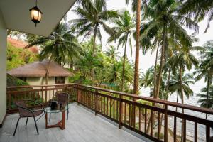 a balcony with a table and chairs and palm trees at Seascape Beach Retreat in Kannur