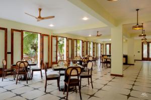 a dining room with tables and chairs and windows at Seascape Beach Retreat in Kannur