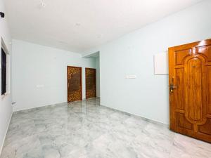an empty room with a wooden door and white walls at Redfox Service Apartment - Ambattur in Jāmb +2 photos