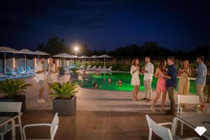 a group of people standing around a pool at night at Ile Hotel in Peschiera del Garda +280 photos