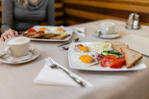 a table with a plate of eggs and toast and a cup of coffee at Hotel Pannonia in Miskolc