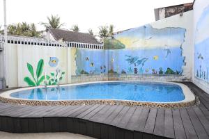 a swimming pool with a mural on the side of a building at Hugo Hotel in Phú Quốc
